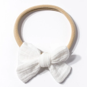 Detail of soft beige elastic baby headband with a large white cotton textured bow