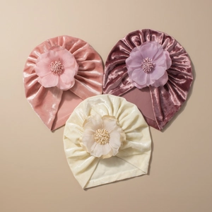 Vue détaillée de bonnets turban en velours pour bébé avec grandes fleurs en mousseline
