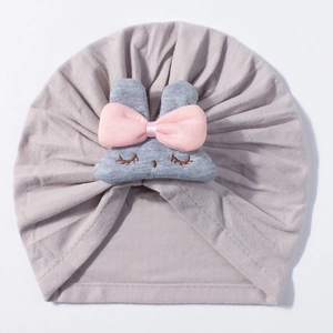 Detailed view of baby turban hat with cute grey plush bunny and pink bow decoration