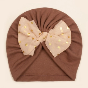 Détail du bonnet turban bébé avec un nœud en maille beige à pois dorés et tissu en peluche