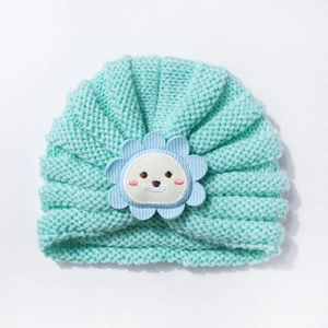 Détail du bonnet turban pour bébé montrant la maille bleu lac et la broderie ours