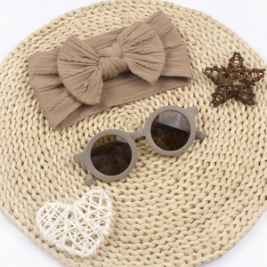 Vue à plat d'un bandeau en tricot à nœud et de lunettes de soleil sur tapis de paille