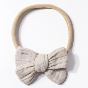 Close-up of beige nylon baby headband featuring double-layered linen bow texture