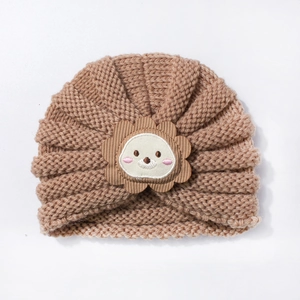 Détail d'un bonnet turban en tricot marron pour bébé avec un joli écusson de lion