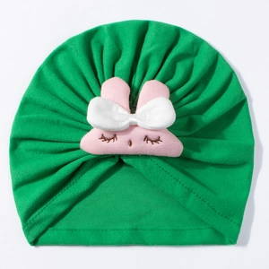 Detail of green knit baby turban hat with a cute pink plush bunny and bow decoration