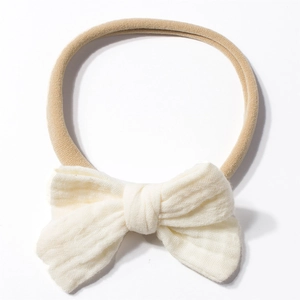 Detail of soft cream cotton gauze bow on elastic nylon headband for infants and babies