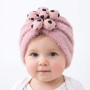Dettaglio del berretto in peluche rosa per neonati con fiore applicato e cuori stampati