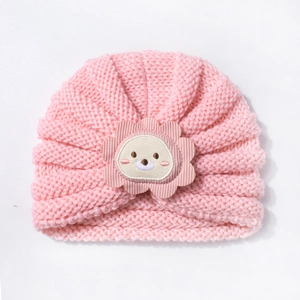 Gros plan du bonnet tricoté rose pour bébé avec texture côtelée et écusson lion mignon