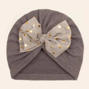 Détail du bonnet bébé gris avec un grand nœud décoré de pois dorés brillants