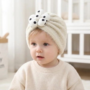 Turbante neonato in peluche bianco crema con un grande fiore a pois su tessuto a maglia morbido