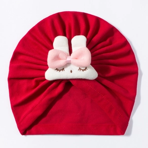 Detail of red newborn turban hat featuring a plush white bunny head with pink bow
