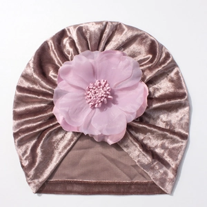 Détail de bonnet turban bébé en velours rose poudré avec une grande fleur en mousseline