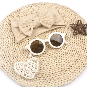 Détail d'un bandeau en maille beige à nœud et de lunettes rondes pour bébés