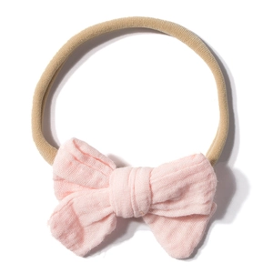 Detailed view of pink gauze bow on a soft nude nylon elastic headband for infants