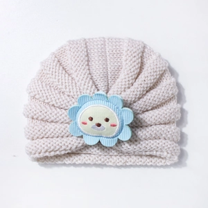 Gros plan détaillé d'un bonnet tricoté beige pour bébé avec écusson lion mignon