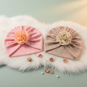 Détail de bonnets turbans pour bébé avec grandes fleurs en tissu et maille texturée