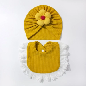 Dettaglio cappello neonato in maglia waffle con fiore e bavaglino in pizzo giallo
