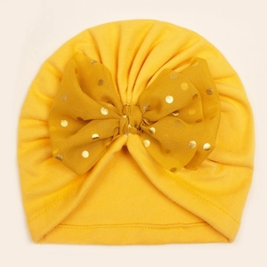 Détail du bonnet turban jaune pour bébé avec grand nœud en résille et pois dorés brillants