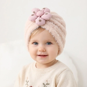 Dettaglio del cappello di peluche per neonati con grande fiore 3D a pois e morbida texture