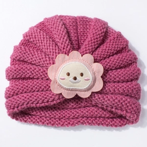 Détail d'un bonnet tricoté rose foncé pour bébé avec applique fleur de lion