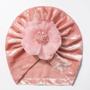 Vue détaillée du bonnet turban pour bébé en velours rose avec fleur en résille