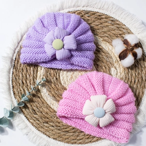 Close-up of soft purple and pink knitted baby hats with textured floral accents and buttons