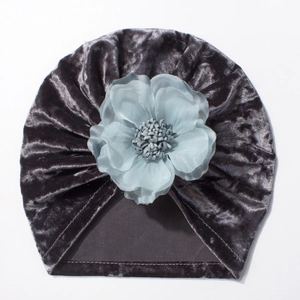 Détail d'un turban en velours gris foncé pour bébé orné d'une fleur bleue en tissu