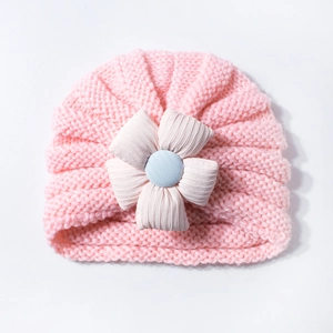 Detailed view of pink knitted baby hat featuring a large soft fabric flower with blue button