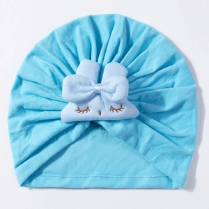Detail of light blue baby turban hat with bow and embroidered sleeping eyes