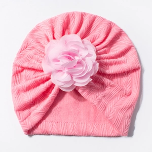 Détail d'un turban pour bébé rose vif avec une grande fleur en mousseline et tissage chevron