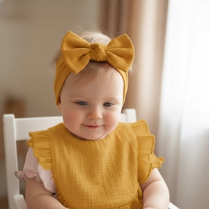 Detail of ginger cotton crepe baby bib with ruffles and matching bow headband set