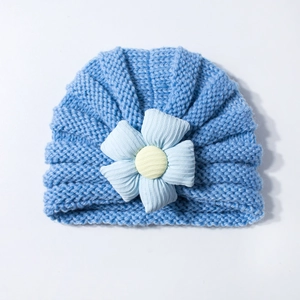 Detailed close-up of blue knitted baby hat featuring a large soft decorative fabric flower