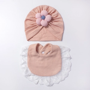Dettaglio del set neonato con turbante a fiori e bavaglino in maglia a nido d'ape