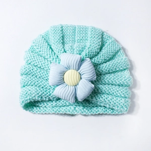 Detailed knit texture of mint green baby hat with a blue 3D fabric flower accent