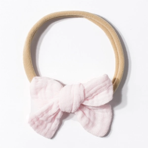 Detail of light pink soft muslin cotton bow on stretchable nude nylon baby headband