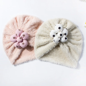 Dettaglio di berretti in peluche per neonati con fiori 3D in rosa confetto e beige