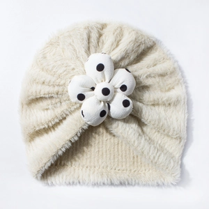 Dettaglio del cappello a turbante per neonati color crema con grande fiore 3D a pois neri