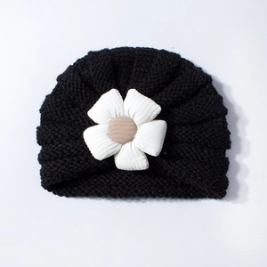 Close-up of black baby knit turban hat featuring a large 3D white fabric flower detail