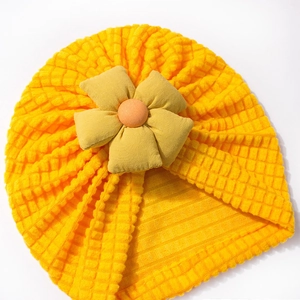 Detailed texture of the yellow knit baby turban hat featuring a large 3D fabric flower