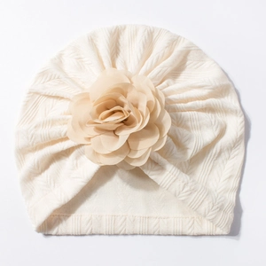 Gros plan du turban pour bébé blanc cassé avec un grand détail de fleur en tissu 3D
