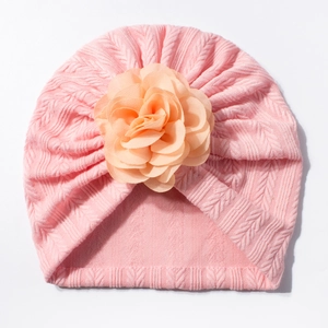 Bonnet turban rose en maille torsadée pour bébé avec grande fleur orange sur fond blanc
