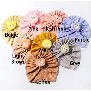 Flat lay of eight colorful waffle knit baby turban hats with cute cartoon fruit patches