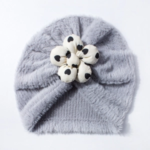 Dettaglio di un cappello di peluche grigio per neonati con fiore di stoffa a motivi di cuori