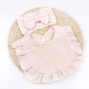 Detail of baby pink cotton gauze bib with ruffled edges and matching bow headband set