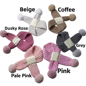 Detail view of knitted baby scarves in six colors featuring cozy faux fur pom-poms