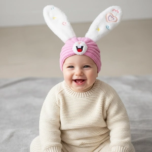 Detail of pink knitted baby hat featuring cute rabbit ears with soft plush and embroidery