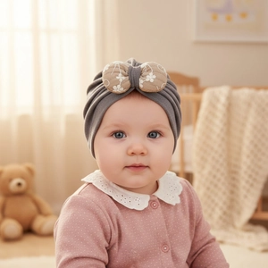 Detail of grey baby turban hat with delicate floral bow in a cozy nursery setting