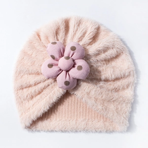 Dettaglio del cappello a turbante in peluche rosa per neonati con grande fiore a pois