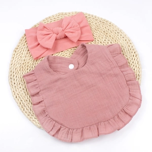 Detailed view of dusty rose cotton bib and matching bow headband on woven mat