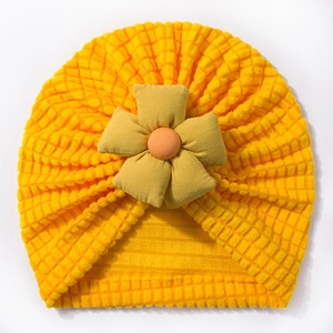 Detailed view of bubble knit texture and floral decoration on yellow baby turban hat